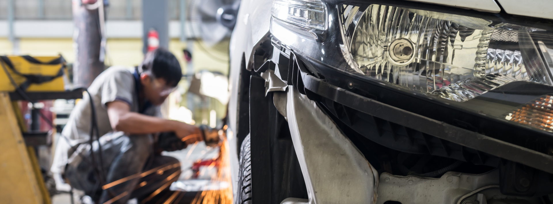 Image of an autobody repair man working on a car.